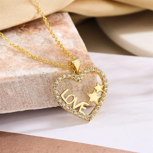 Close-up of gold heart necklace with LOVE lettering and pave-set crystals on marble