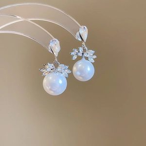 Détail de boucles d'oreilles argentées avec perles en goutte et zircons scintillants en feuilles