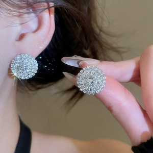 Close-up of sparkling silver round stud earrings with pave-set crystals on model ear