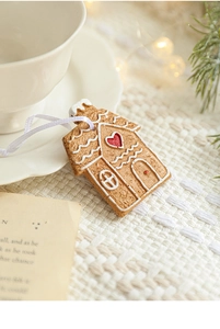 Close-up of a resin gingerbread house ornament with a red heart on white knit fabric