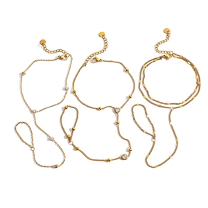 Three gold slave bracelets with zircon heart charms and layered chains on white background