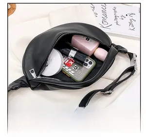 Interior view showing capacity of black leather waist bag with phone and cosmetics