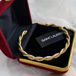 Close-up of golden twisted rope open bangle with red velvet jewelry gift box