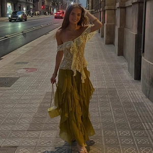 Street style shot of white lace off-shoulder top paired with tiered olive green skirt