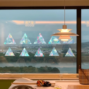 Close-up of rainbow prism window stickers in triangle shape with holographic laser effect
