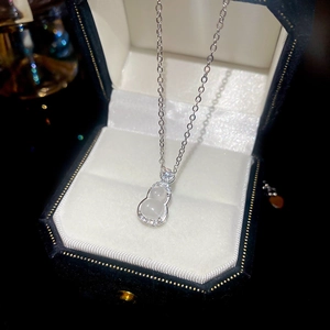 Gros plan du pendentif gourde en argent avec jade blanc et zircons sur velours noir