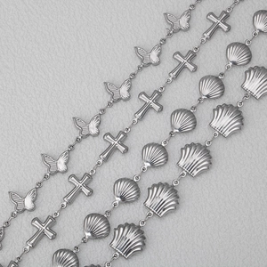 Silver stainless steel butterfly, cross, and shell charm necklaces on a grey leather surface