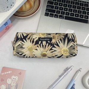 Close-up of a navy floral canvas pencil case with yellow daisy prints and a metal zipper