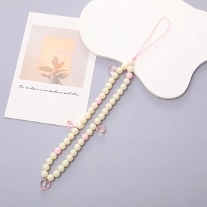 Detalle de la correa para móvil con perlas color crema y colgantes de corazón rosa