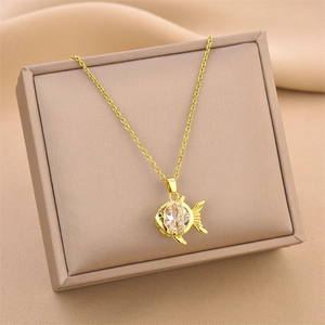 Elegant gold fish pendant necklace with clear crystals on warm velvet gift box background