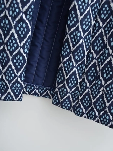 Detail view of deep blue quilted fabric with geometric diamond pattern and stitched lining