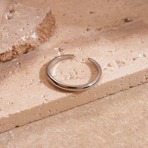 Close-up of a silver geometric adjustable ring on natural textured stone background