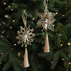 Golden metal snowflake ornaments with gemstones and silk tassels on a Christmas tree