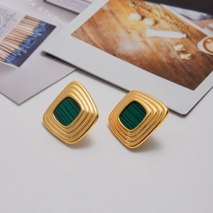 Détail de boucles d'oreilles carrées dorées avec métal multicouche et pierre verte