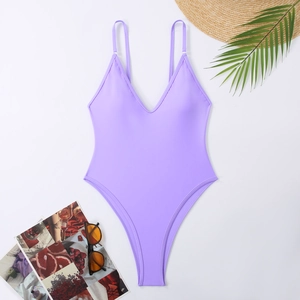 Detailed flat lay of lavender one-piece swimsuit with sunglasses and summer straw hat