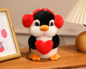 Close-up of plush penguin toy with red heart and headphones in a cozy home setting