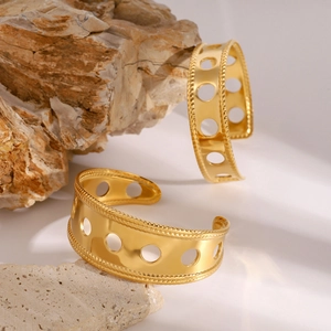 Close-up of a gold hollow geometric bangle bracelet on a natural mineral stone