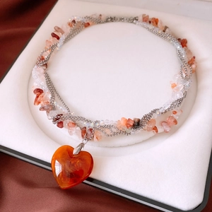 Detail of multi-layered beaded necklace featuring a large orange heart pendant