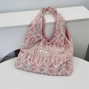 Close-up of pink fabric tote bag with elegant cream lace embroidery and wavy texture