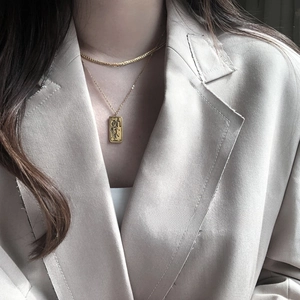 Close-up of layered 18K gold-plated flat snake chain and tarot pendant on a model