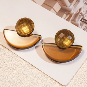 Detailed shot of amber resin geometric fan earrings with gold foil accents on white paper