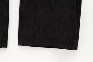 Dettaglio dell'orlo dei pantaloni in denim nero con trama del tessuto e cuciture