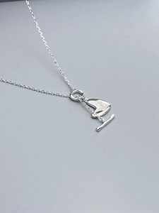 Detail of silver heart necklace with three zircons and OT toggle clasp on grey background