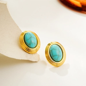 Detail of vintage oval turquoise earrings with an 18K gold finish on a stone background
