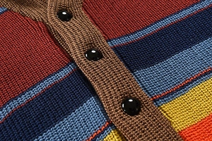 Macro detail of multi-colored striped knit sweater featuring textured fabric and black buttons