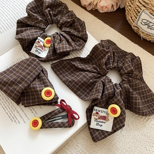 Close-up of brown plaid bow hair clip and scrunchies set with decorative buttons