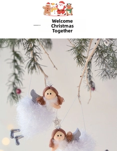 Detail of plush Christmas angel ornaments with silver wings hanging on pine branches