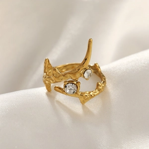 Detail of gold hammer textured ring with two round cubic zirconia on white satin
