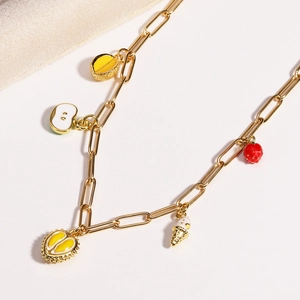 Gold paperclip chain necklace featuring colorful tropical fruit charms on white backdrop