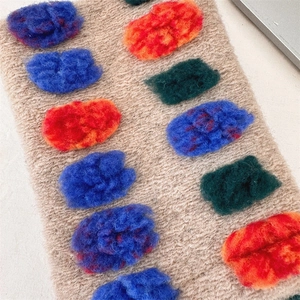 Detail of knit pouch featuring colorful fuzzy pom-poms and warm textured fiber material