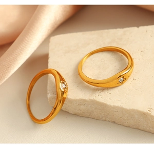 Detail of 18k gold plated north star rings with zircon on textured stone and silk