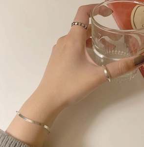Close-up of minimalist 925 silver beaded and streamline rings with snake chain bracelet