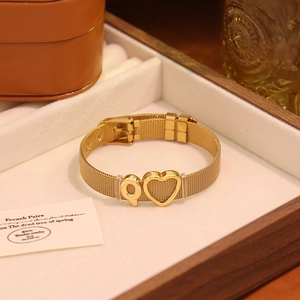 Détail macro du bracelet à mailles dorées en acier inoxydable avec lettre Q et cœur