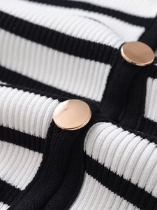 Detail of black and white striped knit fabric with polished gold metal buttons