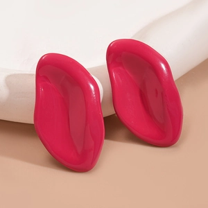 Macro view of rose red irregular geometric resin earrings on a stone platform