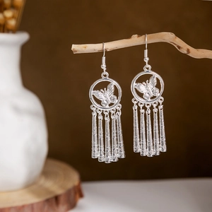 Detail of silver ethnic butterfly earrings with long fringe tassels on a branch