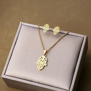 Detailed view of golden Hamsa Hand jewelry set with necklace and earrings on a velvet box