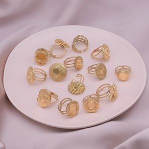 Set of 13 golden stainless steel geometric rings on a soft pink silk fabric background