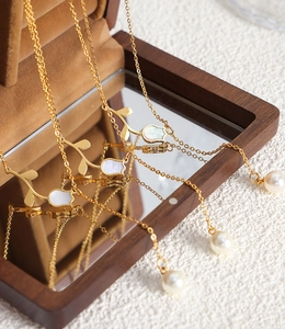 Detailed view of tulip pendants with white shell and pearls over a wooden mirror box