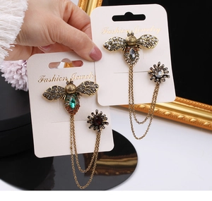 Detailed macro view of vintage bee brooches with double metal chains and sparkling rhinestones