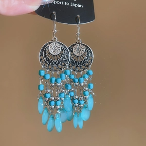 Detail of vintage bohemian silver drop earrings with light blue beads and tassels