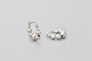 Macro detail of S925 sterling silver beaded hoop earrings with a polished metallic finish