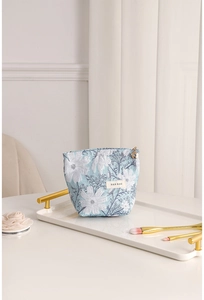 Close-up of blue jacquard makeup bag with white floral patterns and golden zipper