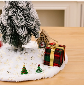 Detail of white plush Christmas tree skirt with golden snowflake patterns on wood