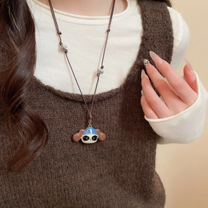 Close-up of a cartoon dog pendant with blue cap and sunglasses on a brown cord