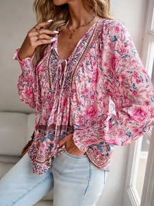 Detail of pink Bohemian floral blouse with V-neck, tassel ties, and elastic cuffs